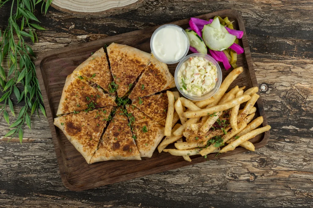 Sliced savory flatbread served with fries and sides