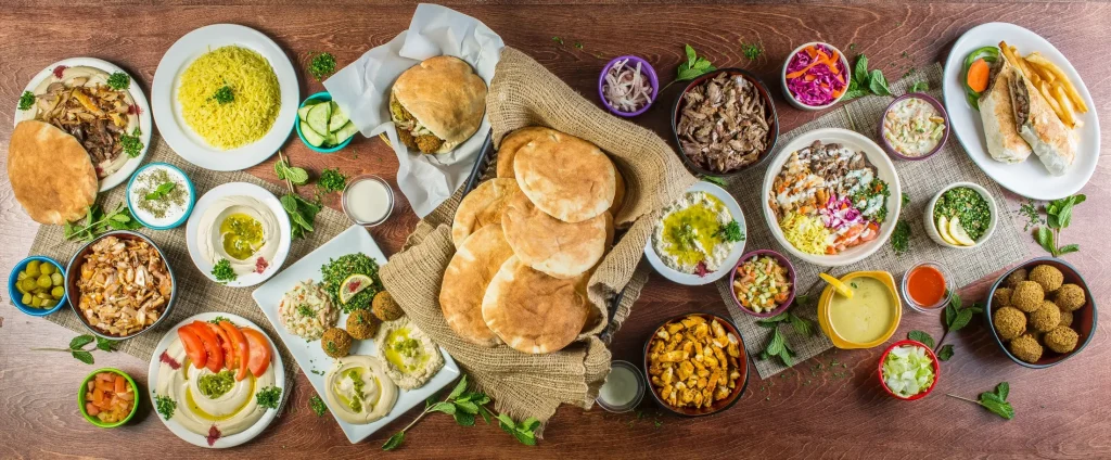 A table full of Mediterranean dishes, wraps, bowls and sides