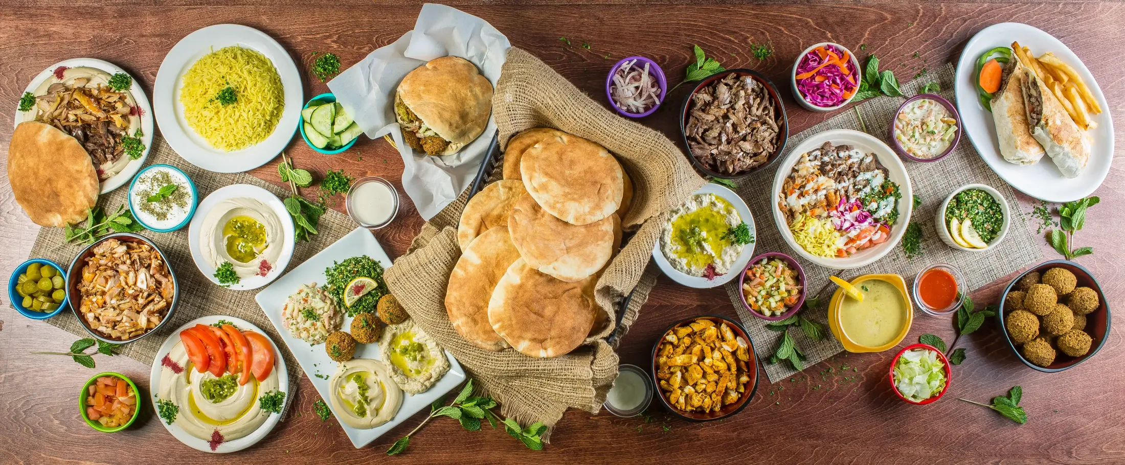 Colorful spread of Mediterranean food, wraps, bowls and sides