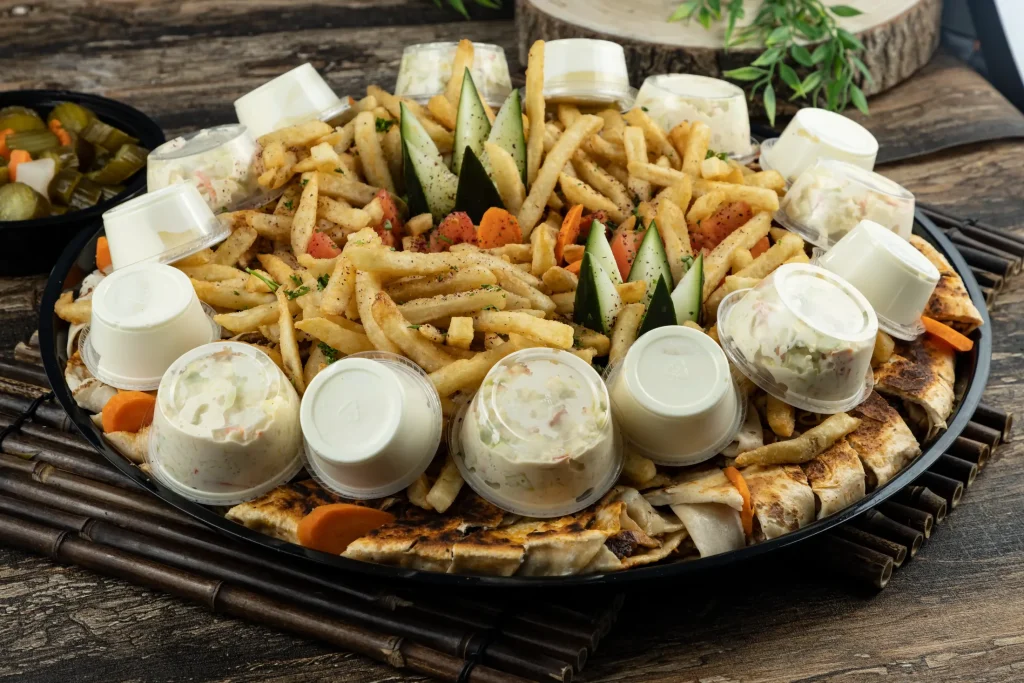 Large party platter with meat, fries, vegetables and sauces